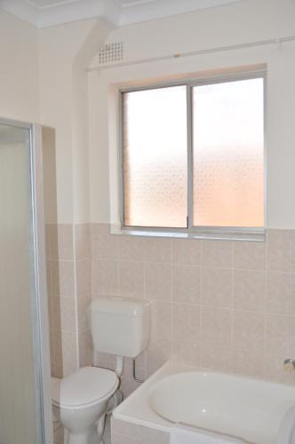 a bathroom with a toilet and a tub and a window at Accommodation Sydney Kogarah 2 Bedroom Budget Apartment with Balcony in Sydney