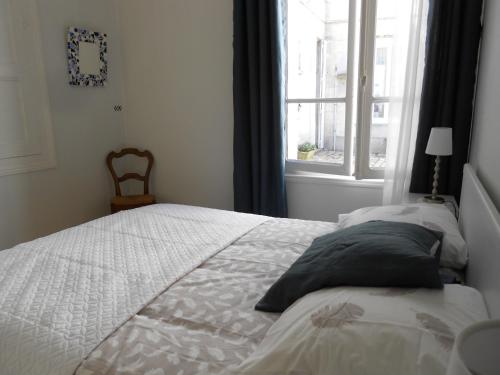 ein Schlafzimmer mit einem weißen Bett und einem Fenster in der Unterkunft 8 Rue de la Petite Bilange " Maison du Centre" in Saumur