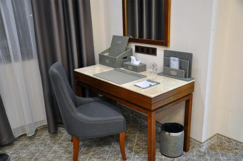a desk with a laptop and a chair in a room at Parliament Palace Hotel in Khujand