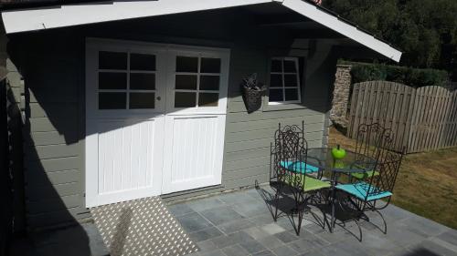 a shed with a white door and a table and chairs at Gîte Au Coeur de Champlon in Champlon