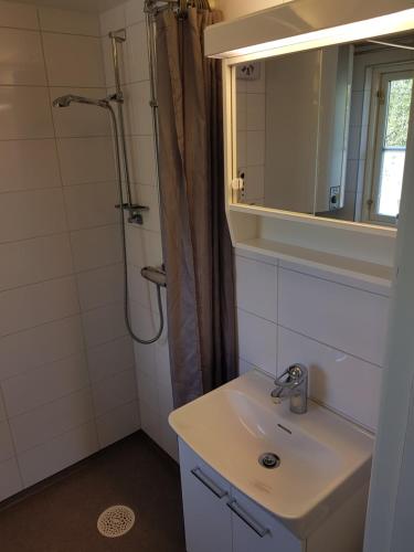 y baño con lavabo y ducha con espejo. en Toppstugan en Åkerö