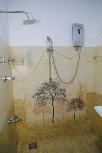 a bathroom with a shower with a tree mural on the wall at Eagle Homestay in Tangalle