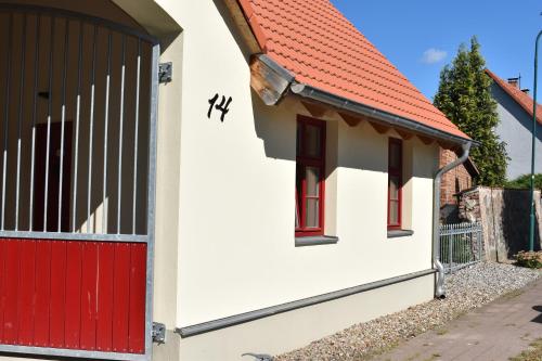 a red door on a white house with a red roof at Apfelhof Biesenbrow in Biesenbrow