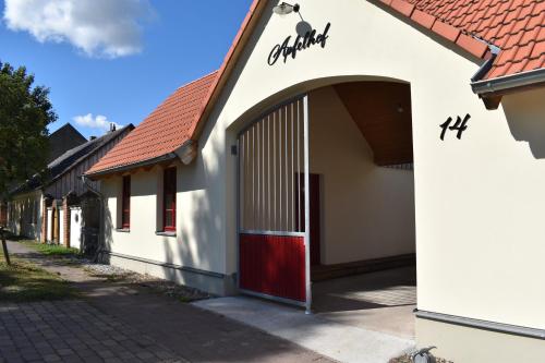 um edifício branco com uma porta vermelha numa rua em Apfelhof Biesenbrow em Biesenbrow