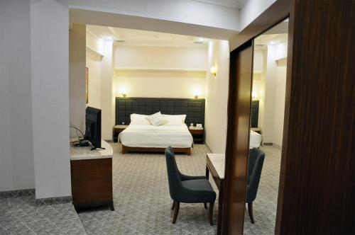 a hotel room with a bed and a desk and chairs at Parliament Palace Hotel in Khujand