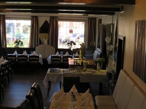 uma sala de jantar com mesas, cadeiras e janelas em Gasthof Einhaus em Borken
