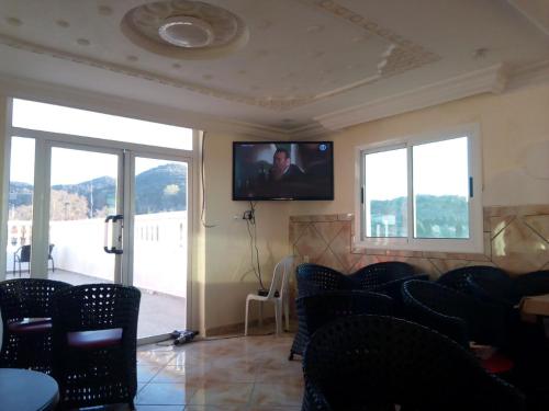 a waiting room with chairs and a flat screen tv at Hotel Ain Leuh in Aïn Leuh