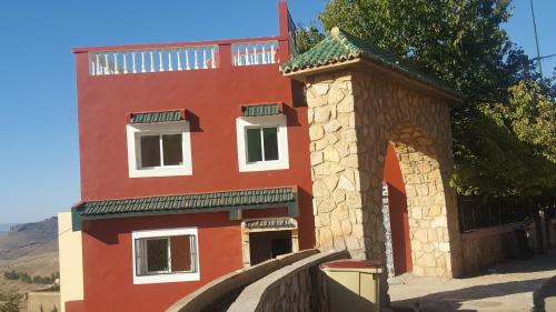 a red building with an arch and a tower at Hotel Ain Leuh in Aïn Leuh