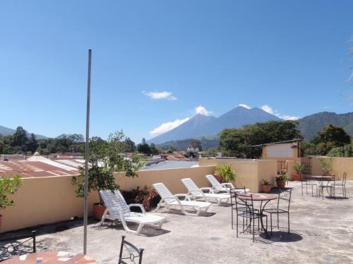 a group of chairs and tables on a patio with mountains at Posada San Vicente by AHS in Antigua Guatemala