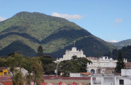 a mountain in the background of a city with a building at Posada San Vicente by AHS in Antigua Guatemala