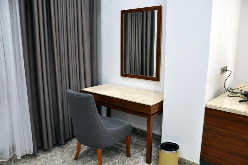 a desk with a mirror and a chair in a room at Parliament Palace Hotel in Khujand