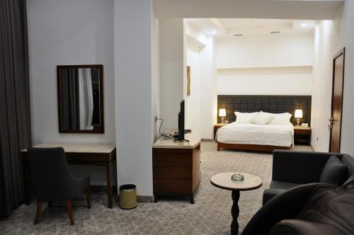 a bedroom with a bed and a desk and a couch at Parliament Palace Hotel in Khujand