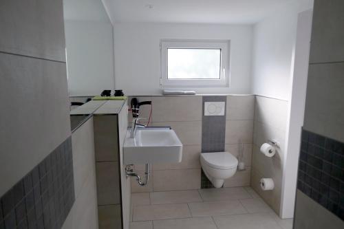 a bathroom with a toilet and a sink and a window at Messeappartement Unterrath in Düsseldorf