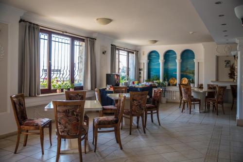 jadalnia ze stołami, krzesłami i oknami w obiekcie Victoria Hotel Nessebar w Nesebarze
