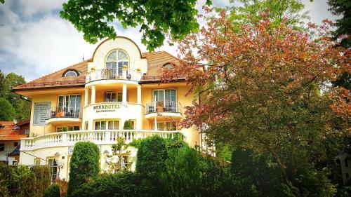 Cette grande maison jaune possède un balcon blanc. dans l'établissement Parkhotel Bad Faulenbach, à Füssen