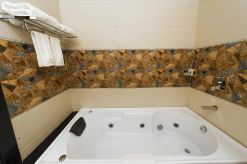a white bath tub in a bathroom with tiles at Costa Riviera Hotel in Varanasi