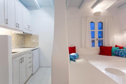 een witte keuken met rode en blauwe kussens bij Naxian Riviera Exclusive Seafront Suites, Junior Suite in Agios Prokopios