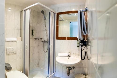 ein Bad mit einer Dusche, einem Waschbecken und einem WC in der Unterkunft Hotel Obermayr in Ebenau
