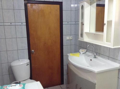 a bathroom with a toilet and a sink and a wooden door at Chez Taia et Véro in Tiputa