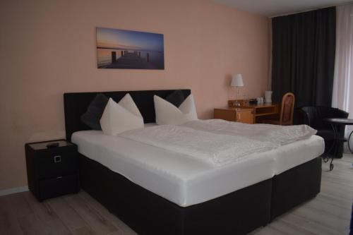 a bedroom with a large bed with white sheets and pillows at Hotel Ammerland garni in Wilhelmshaven