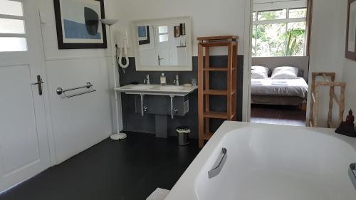 La salle de bains est pourvue d'une baignoire, d'un lavabo et d'un lit. dans l'établissement Habitation Villa Les Cassias, à Petit-Bourg