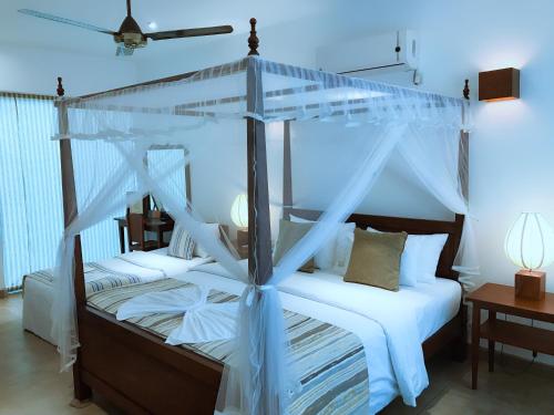 a bedroom with a canopy bed with white sheets at Coza Ceylon in Mount Lavinia
