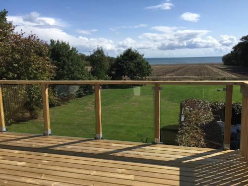 a wooden deck with a view of a field at Hegnsly in Odder