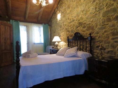 a bedroom with a bed and a stone wall at Neverending Bierzo in Pobladura de las Regueras