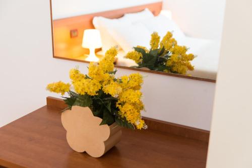 a vase of yellow flowers on a table next to a bed at Doge Veneziano in Mestre