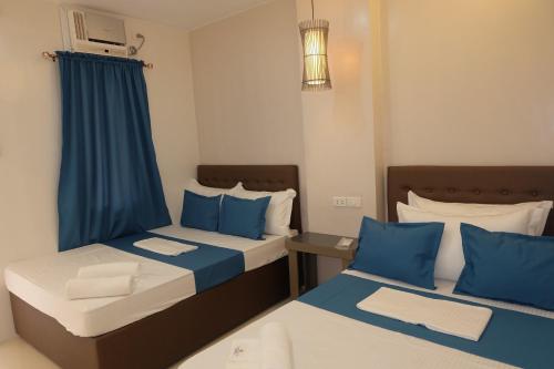 dwa łóżka w pokoju niebiesko-białym w obiekcie Laule'a Hostel w mieście El Nido
