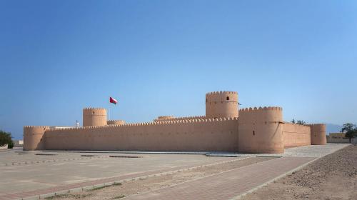a large brick building with a flag on top of it at Six Senses Zighy Bay in Dibba