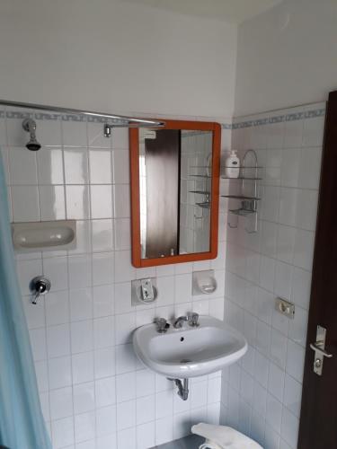 a white bathroom with a sink and a mirror at Albergo Ristorante Borghese in Montereale Valcellina