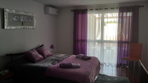 Rabo de PeixeにあるCasa do Sossego - Guesthouseのベッドルーム1室(ベッド1台付)、紫色のカーテン付きの窓が備わります。