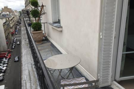 une chaise assise sur le balcon d'un bâtiment dans l'établissement Appartement Champs Elysées, à Paris