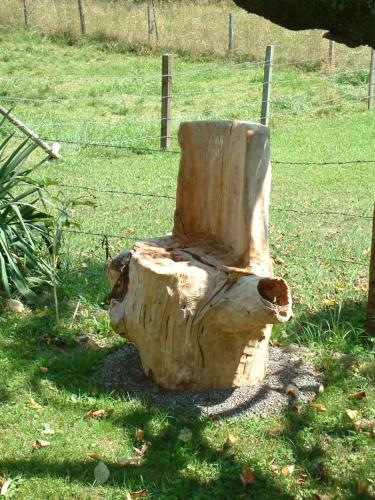 a statue of a tree stump sitting in the grass at Ferienwohnung Woid Mandl in Velden am Wörthersee