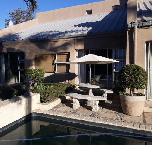 a patio with a table and umbrella next to a pool at 35 on Basil in Caledon