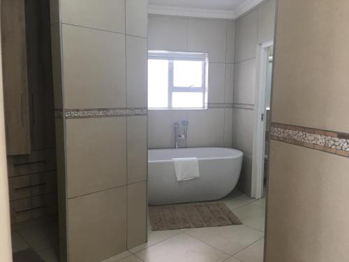 Un baño blanco con bañera y ventana. en Villa Hakmka, en Jeffreys Bay