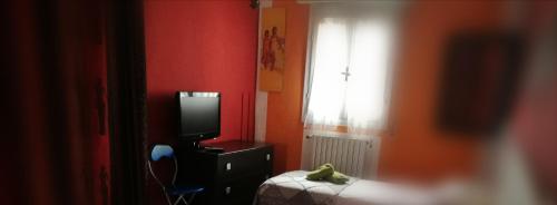 1 dormitorio con TV, 1 cama y ventana en B&B PORTA APPIA, en Imola