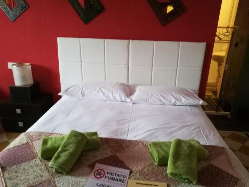 Una cama blanca con dos almohadas verdes. en B&B PORTA APPIA, en Imola