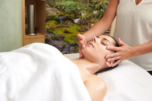 a woman getting a massage from a woman laying in bed at Maison de la Garenne & Spa in Vannes
