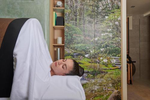 a man laying in a bed with his head under a blanket at Maison de la Garenne & Spa in Vannes