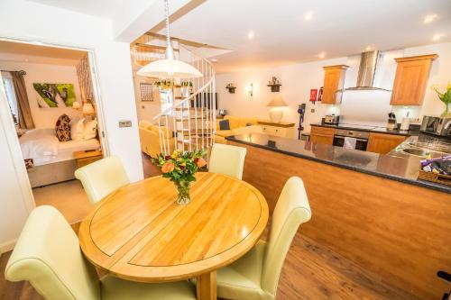 a kitchen and dining room with a wooden table and chairs at Swallows Nest - Covehurst Bay Cottage in Hastings