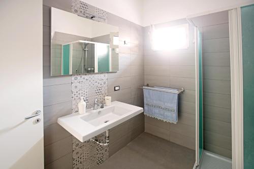 a white bathroom with a sink and a mirror at Ciraccio Apartments in Procida