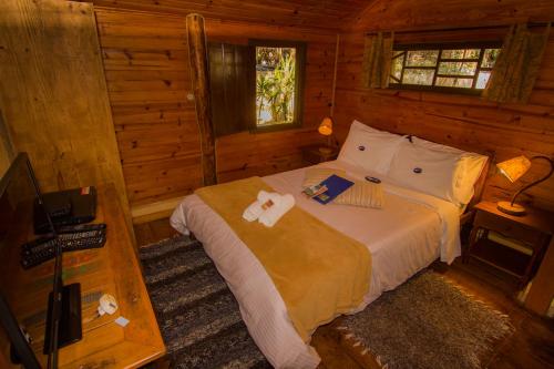 Un dormitorio con una cama en una cabaña de troncos en Pousada Canto da Lua, en São Bento do Sapucaí