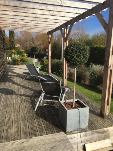 a chair on a deck with a tree in a planter at Chambres d'hotes ASAM in Lherm