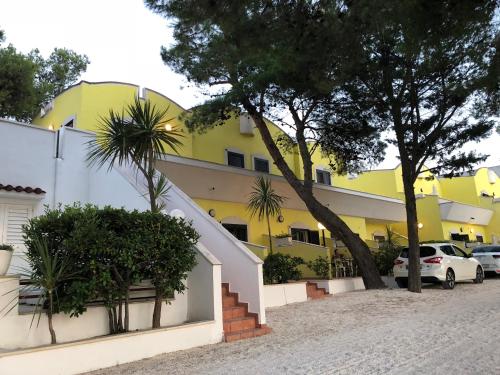 un bâtiment jaune avec des voitures garées devant lui dans l'établissement Argeste Club Vacanze, à Vieste