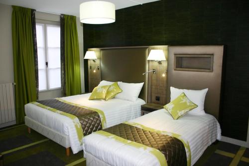 two beds in a hotel room with green curtains at Hotel Bellevue in Amboise