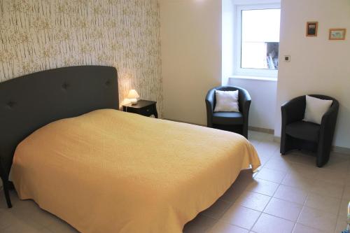 a bedroom with a bed and two chairs and a window at Domaine du Jardin " Chambres d'hôtes " in Saint-Jean-de-la-Haize