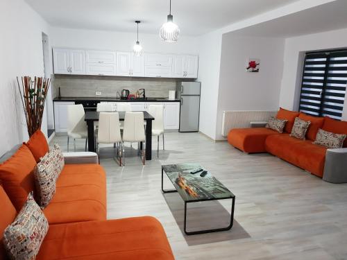 Palm Rezidential في سيبس: غرفة معيشة مع أريكة برتقالية وطاولة