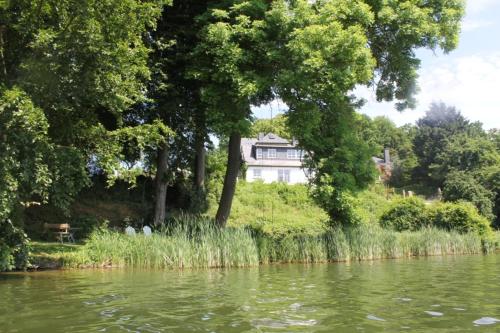 a house sitting on top of a hill next to a river at Ferienhaus direkt am Schmalensee in Schmalensee